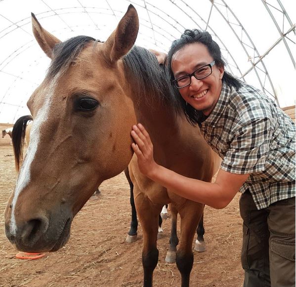 Jimmy Ung takes a photo with a horse while visiting P.E.I. on his journey across Canada.