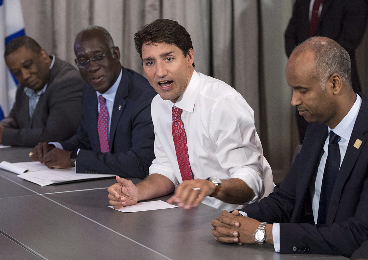 Prime Minister Justin Trudeau, MP Emanuel Dubourg, left, and Ahmed Hussen, right, Federal Minister of Immigration, Refugees and Citizenship, meet with Haitian community leaders, Wednesday, August 23, 2017 in Montreal. 