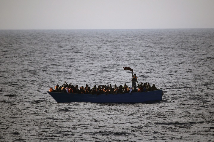 FILE- In this Friday, Feb. 3, 2017 file photo, migrants and refugees wave for help from inside a wooden boat off the coast of Libya.