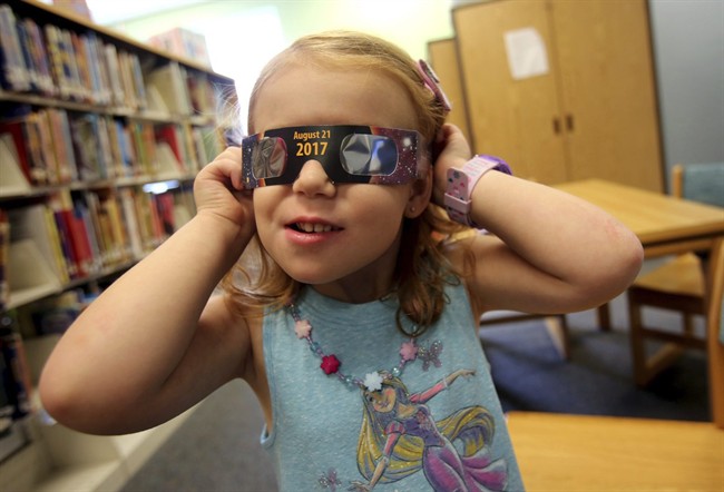 FILE - In this Wednesday, Aug. 2, 2017 file photo, Emmalyn Johnson, 3, tries on her free pair of eclipse glasses at Mauney Memorial Library in Kings Mountain, N.C. Glasses are being given away at the library for free while supplies last ahead of the big event on Aug. 21. 