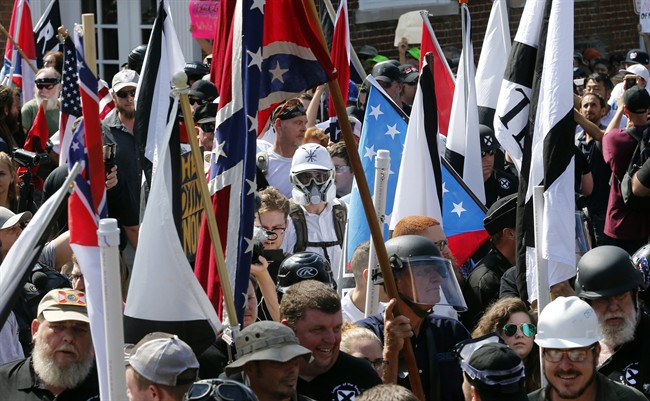 In this Saturday, Aug. 12, 2017 file photo, white nationalist demonstrators walk into the entrance of Lee Park surrounded by counter demonstrators in Charlottesville, Va. 