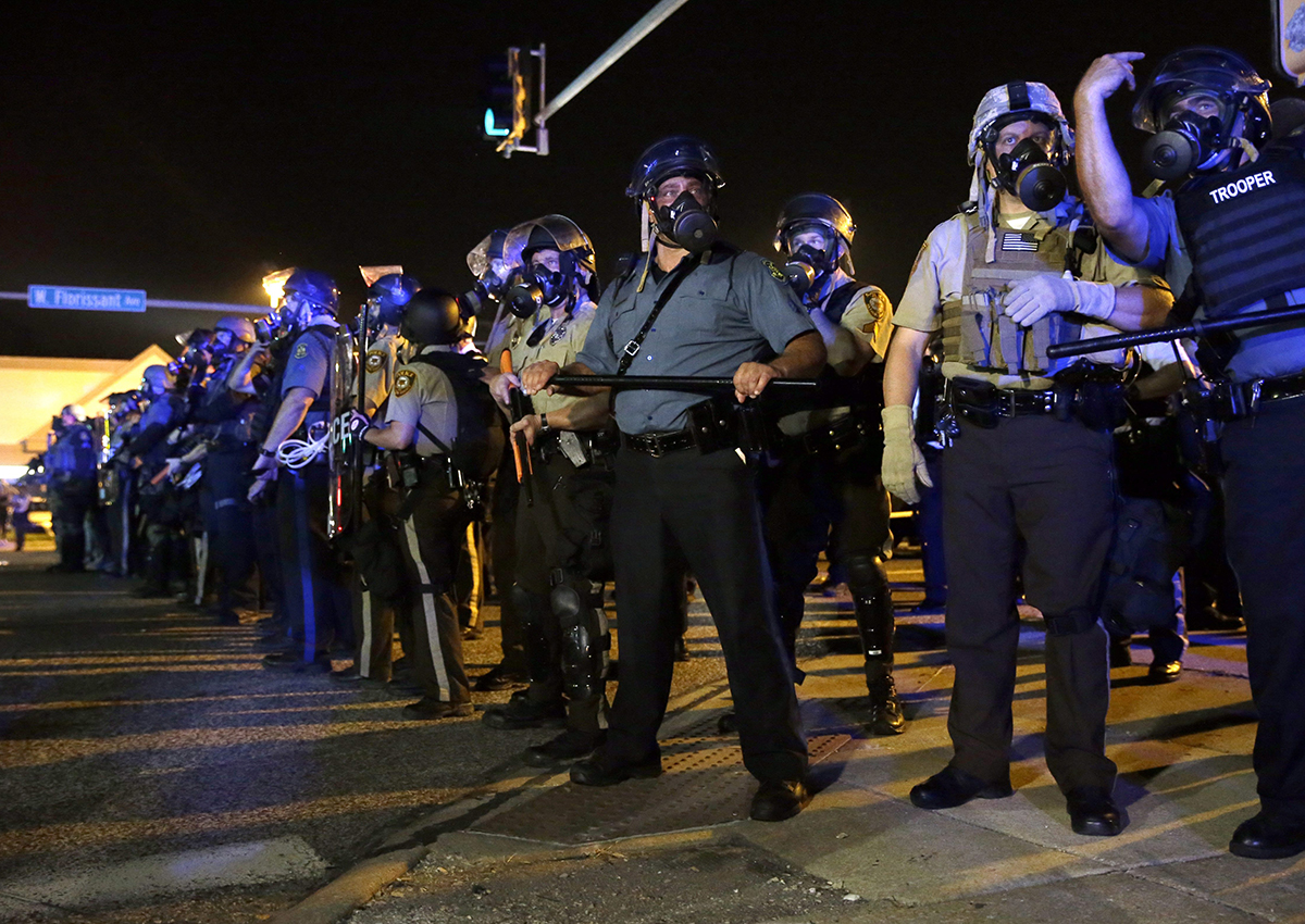 In this photo taken Aug. 18, 2014, police is riot gear work to disperse a crowd of protesters in Ferguson, Mo. 