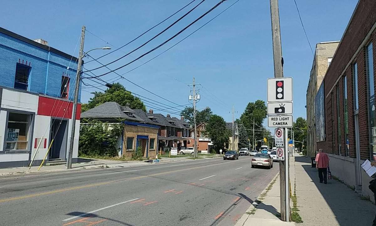 A road on a sunny day with a sign warning of a red light camera.