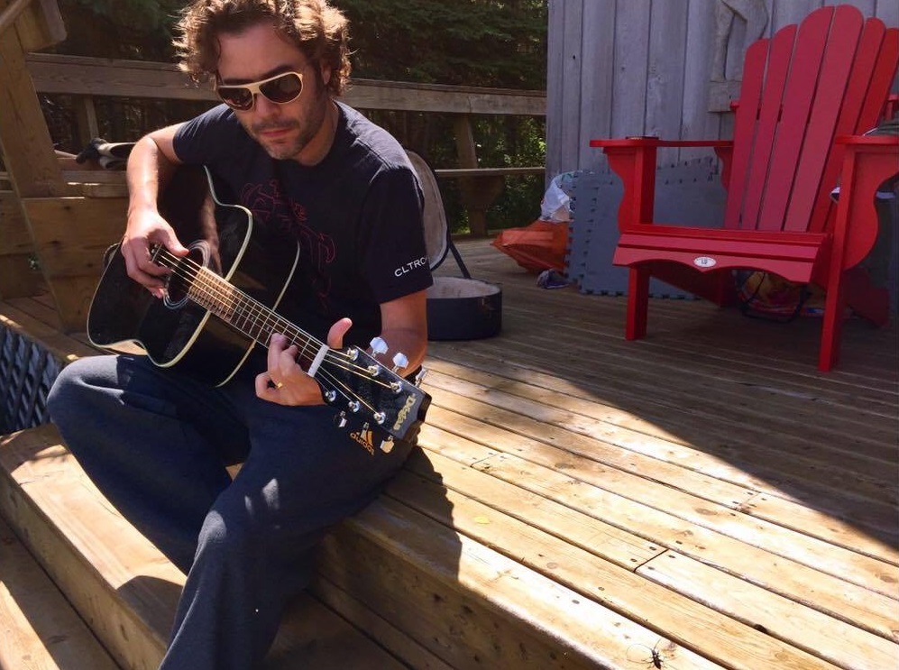 Adam Clarke plays a guitar at his home. He is turning part of a fallen tree from the intense Montreal thunder storm into a guitar.