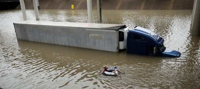 A man floats past a truck submerged on a freeway flooded by Tropical Storm Harvey on Sunday, Aug. 27, 2017, near downtown Houston. The remnants of Hurricane Harvey sent devastating floods pouring into Houston Sunday as rising water chased thousands of people to rooftops or higher ground. 