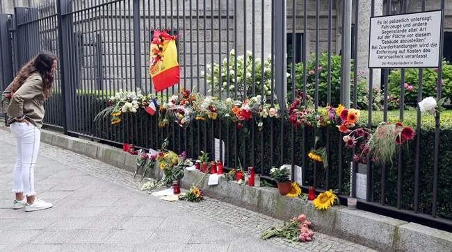 A woman looks at the symbols of condolence people have laid down for the victims of the terror attacks that killed 14 people and wounded over 120 in Barcelona , Spain, in front of the Spanish embassy in Berlin, Germany, Monday, Aug. 21, 2017. 
