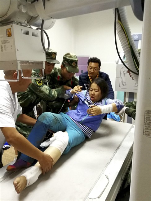 Rescue workers assist an injured woman onto a hospital bed in the aftermath of an earthquake in Jiuzhaigou county in southwestern China's Sichuan province Wednesday Aug. 09, 2017. A strong earthquake shook a mountainous region in southwestern China near a famous national park, killing people and knocking out power and phone networks. (Chinatopix Via AP).