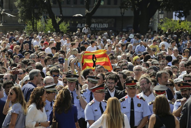 People holding a Catalan flag gather for a minute of silence in memory of the terrorist attacks victims in Las Ramblas, Barcelona, Spain, Friday, Aug. 18, 2017. Spanish police on Friday shot and killed five people carrying bomb belts who were connected to the Barcelona van attack that killed at least 13, as the manhunt intensified for the perpetrators of Europe's latest rampage claimed by the Islamic State group.