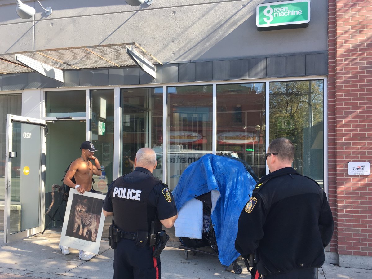Officers watch a squatter pack up belongings after booting him out of the TD Bank on Osborne Street.