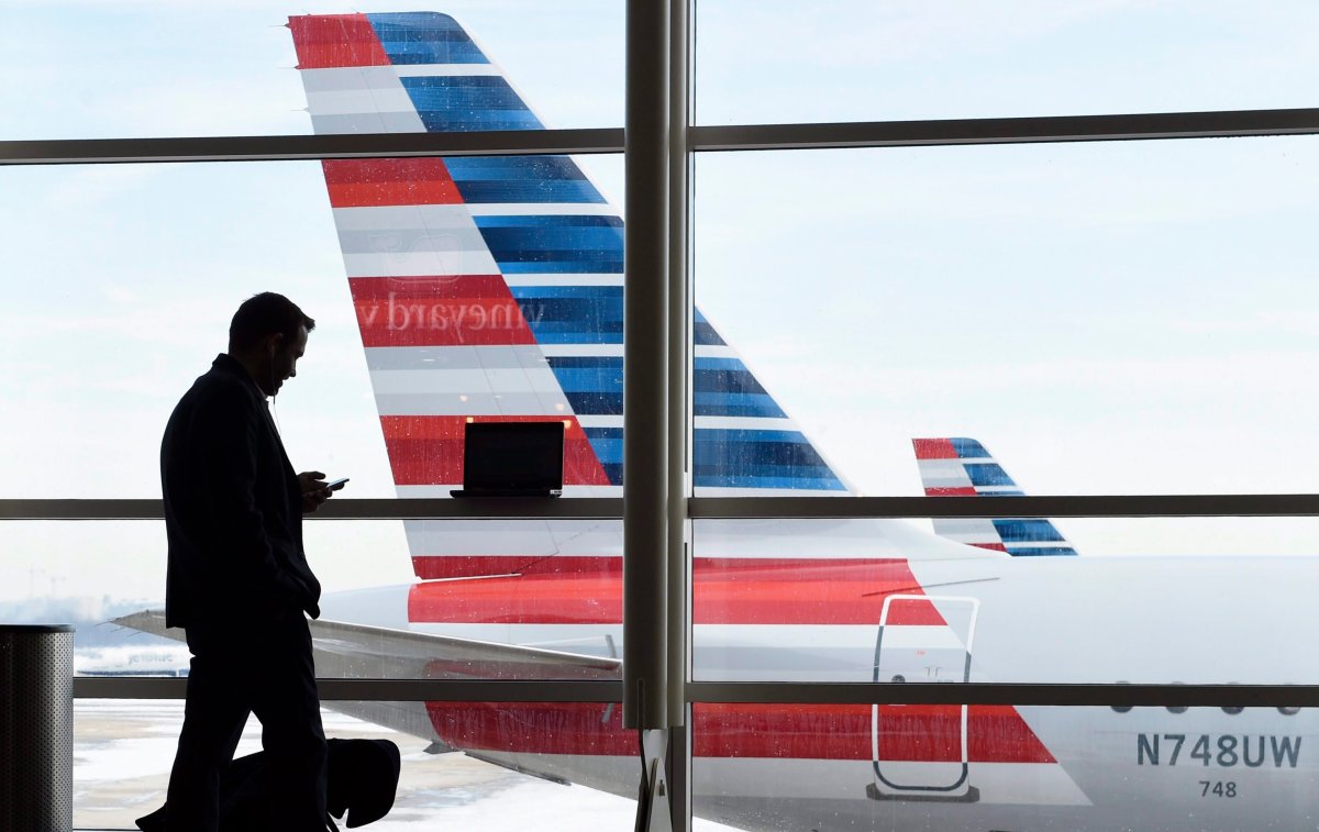 In this Jan. 25, 2016, file photo, a passenger talks on the phone as an American Airlines jets sit parked at their gates at Washington's Ronald Reagan National Airport.