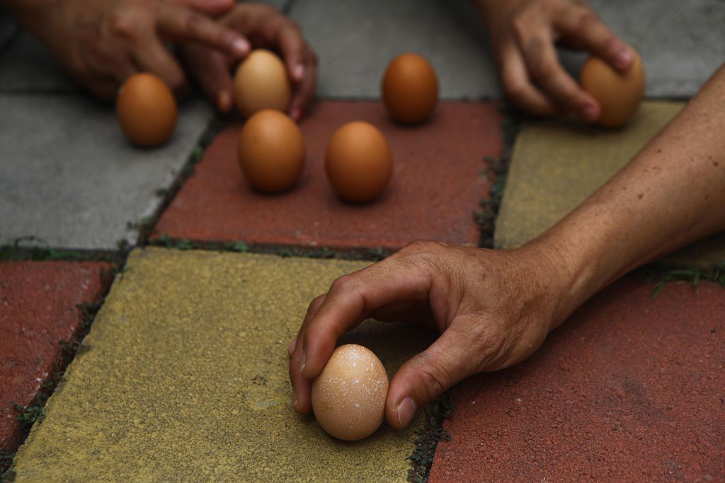 People try to get eggs to stand upright, believed to invite good luck, Tangerang, Indonesia.