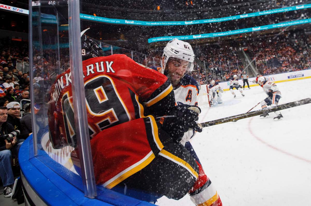 Calgary Flames forward Hunter Shinkaruk (49) is checked by Edmonton Oilers defenceman Eric Gryba (62) during first period NHL preseason split-squad hockey action in Edmonton, Alta., on Monday September 18, 2017.