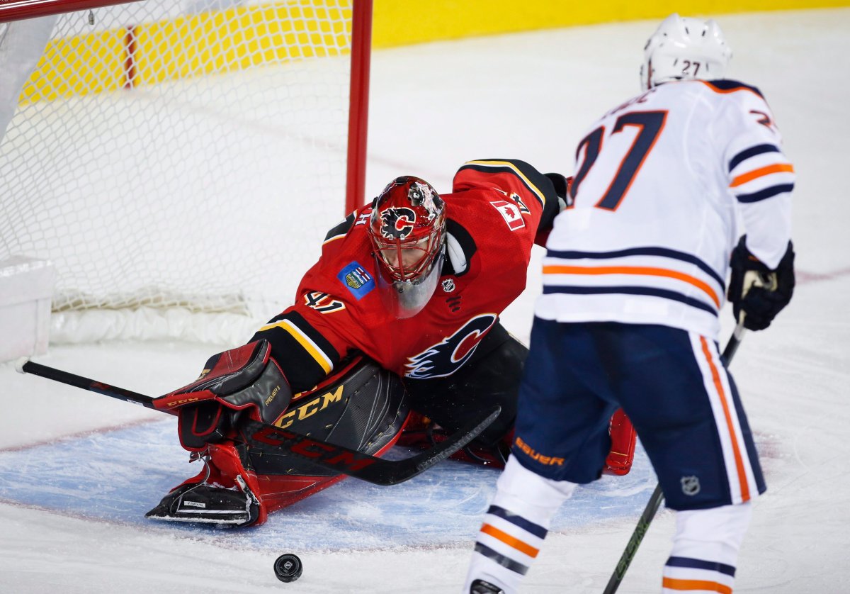Edmonton Oilers forward Milan Lucic, right, has the puck swatted away from him by Calgary Flames goalie Mike Smith during second period NHL preseason split-squad hockey action in Calgary, Monday, Sept. 18, 2017.