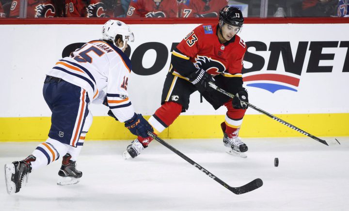 Calgary Flames forward Johnny Gaudreau and Edmonton Oilers forward Mitch Callahan, left, chase the puck during second period NHL preseason split-squad hockey action in Calgary, Monday, Sept. 18, 2017.
