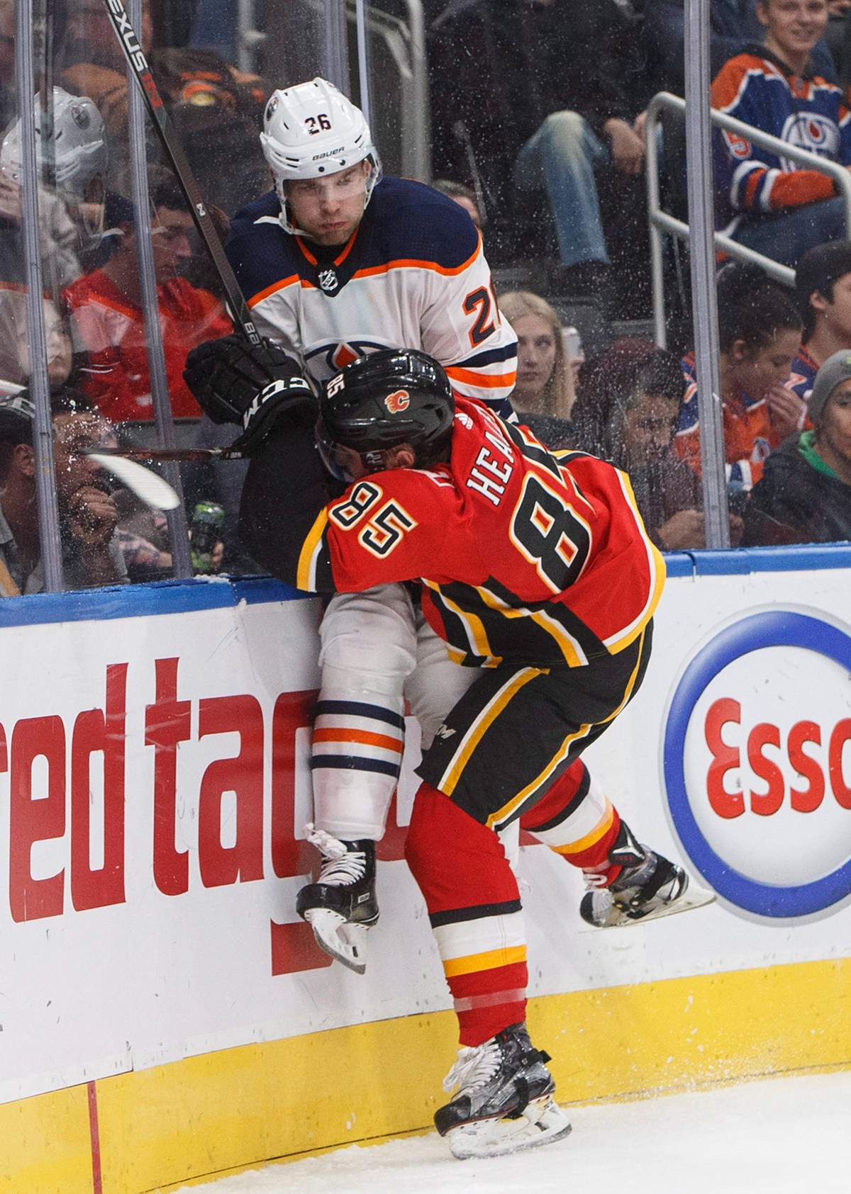 Calgary Flames defenceman Josh Healey (85) checks Edmonton Oilers forward Iiro Pakarinen (26) during second period NHL preseason action in Edmonton, Alta., on Monday September 18, 2017.