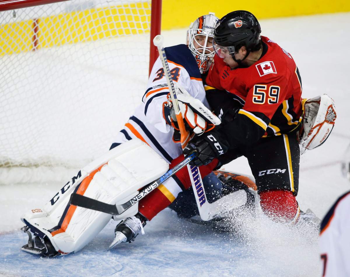 Edmonton Oilers goalie Nick Ellis, left, stops Calgary Flames forward Dillon Dube from scoring during third period NHL preseason split-squad hockey action in Calgary, Monday, Sept. 18, 2017.