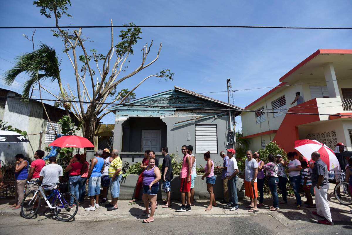 People affected by the passage of Hurricane Maria wait in line at Barrio Obrero to receive supplies from the national Guard, in San Juan, Puerto Rico, Sunday, Sept. 24, 2017.