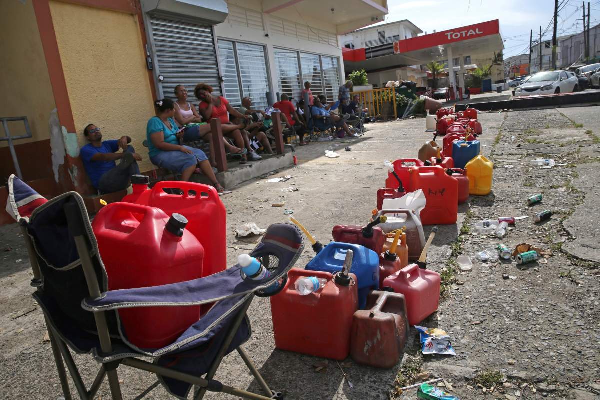 Residents line up gas cans as they wait for a gas truck to service an empty gas station, in the aftermath of Hurricane Maria in Loiza, Puerto Rico, Sunday, Sept. 24, 2017.