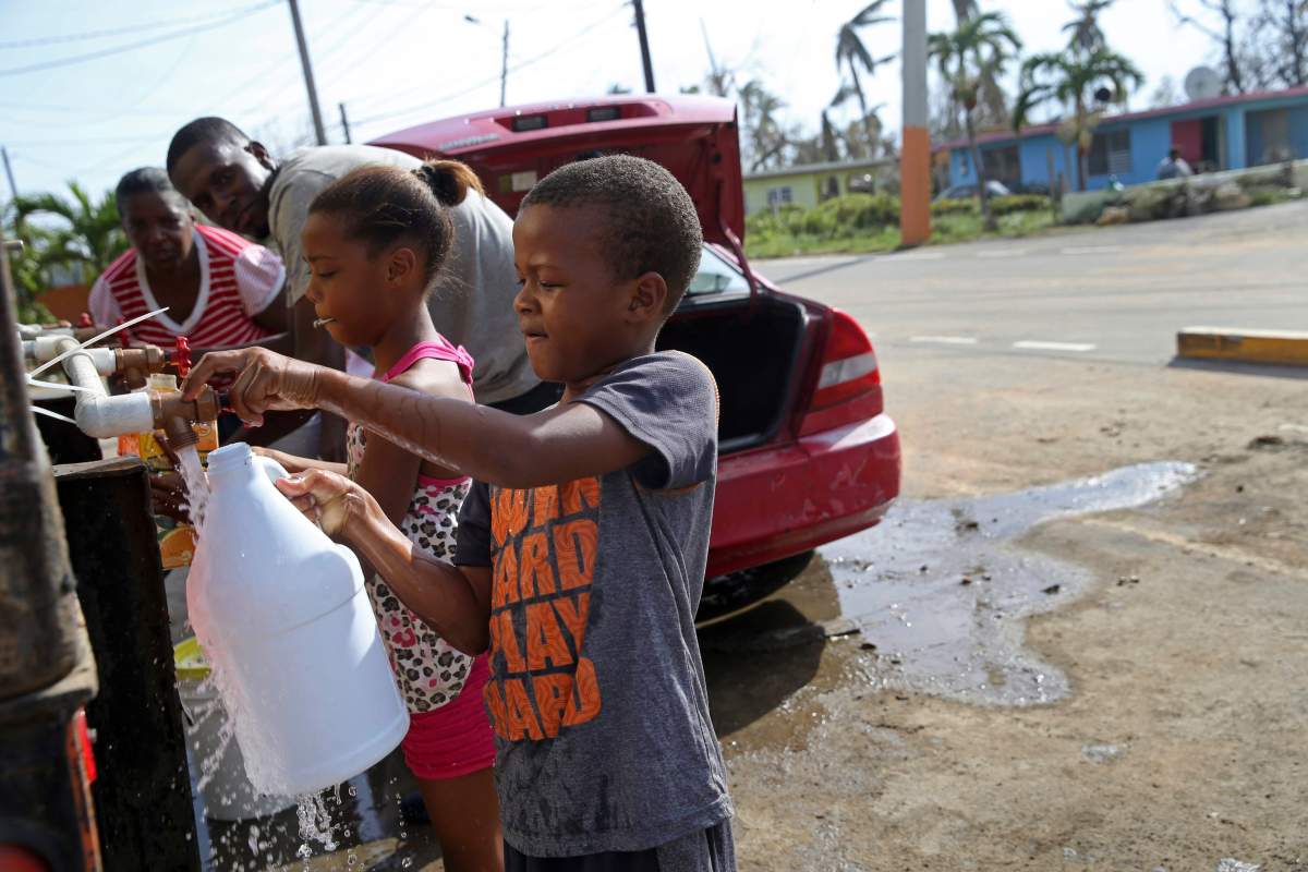 Children fill up bottles with water at a water distribution point, in the aftermath of Hurricane Maria in Loiza, Puerto Rico, Sunday, Sept. 24, 2017.