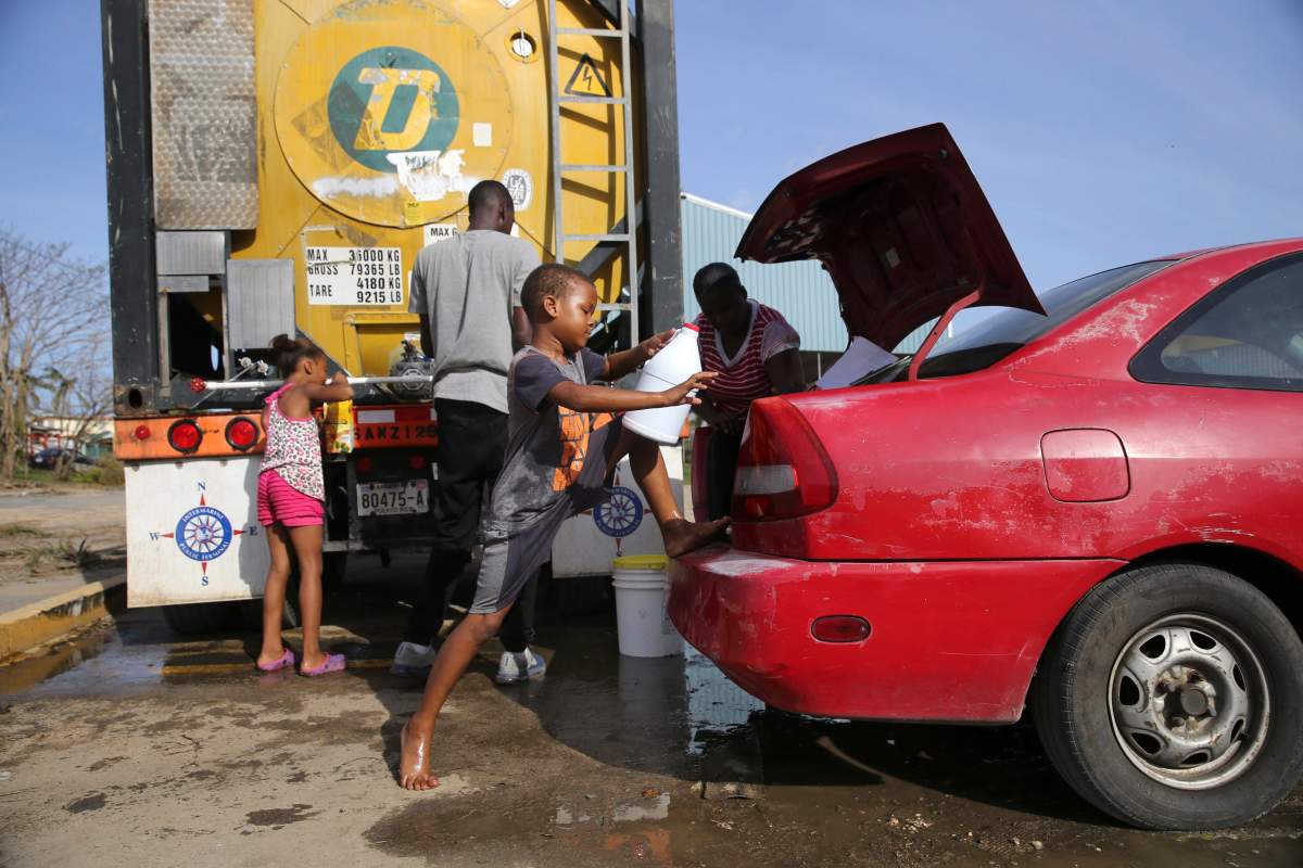 Children fill up bottles with water at a water distribution point, in the aftermath of Hurricane Maria in Loiza, Puerto Rico, Sunday, Sept. 24, 2017. Federal aid is racing to stem a growing humanitarian crisis in towns left without fresh water, fuel, electricity or phone service by the hurricane.