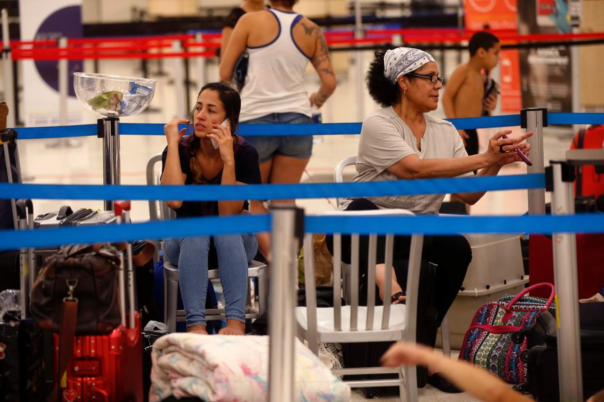 Stranded passengers who are sleeping inside the main international airport in San Juan, communicate on their phones, in San Juan Puerto Rico, Monday, Sept. 25, 2017.