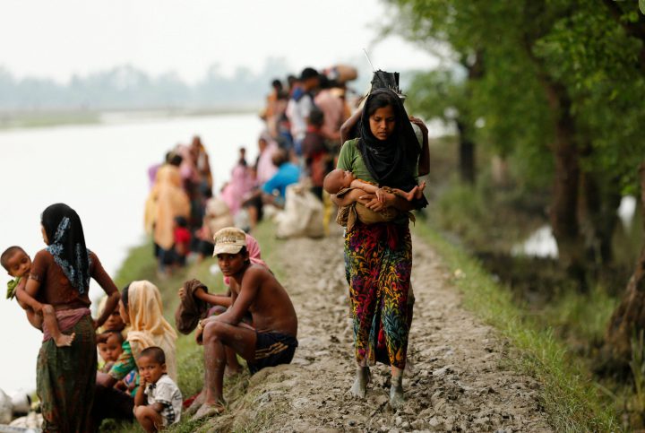 A Rohingya refugee woman with her child walks on the muddy path after crossing the Bangladesh-Myanmar border in Teknaf, Bangladesh.