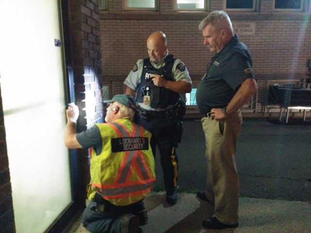 A locksmith and RCMP officers attempt to gain entrance to the UPS store.