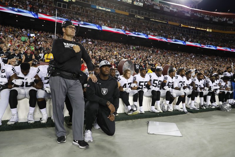Oakland Raiders players take a knee during the U.S. national anthem.