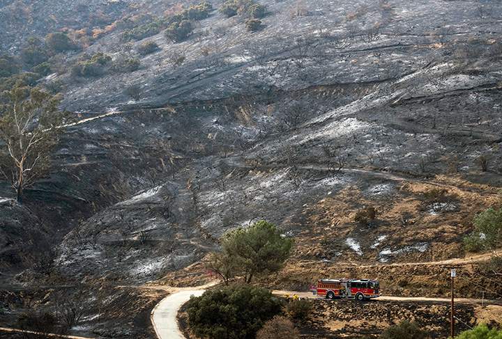 A fire engine drives past a burned area from a wildfire Monday, Sept. 4, 2017, in the Sunland-Tujunga section of Los Angeles.