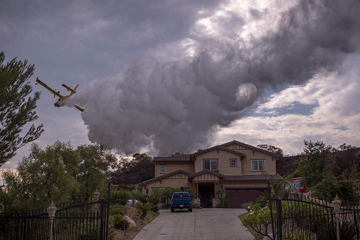 A Super Scooper CL-415 firefighting aircraft from Canada makes a drop to protect a house during the La Tuna Fire on September 3, 2017 near Burbank, California.