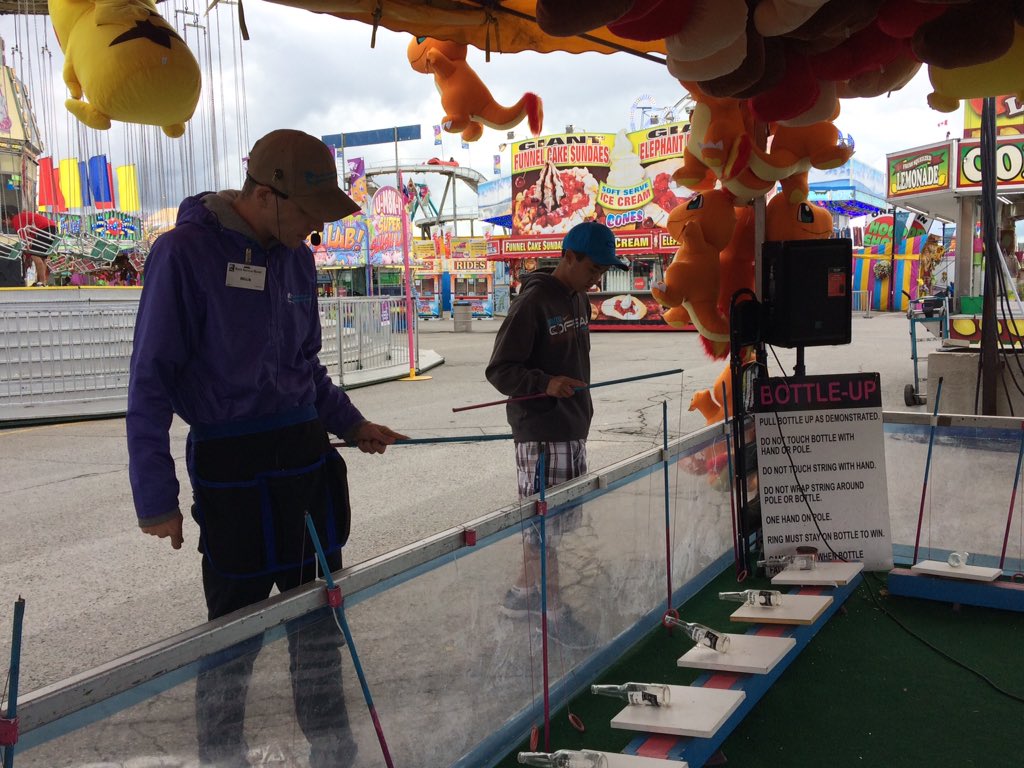 Daniel Lam-Sidun, a third-year Western student, gets some advice on how to master the Bottle Up game at the Western Fair, on Friday September 8, 2017.