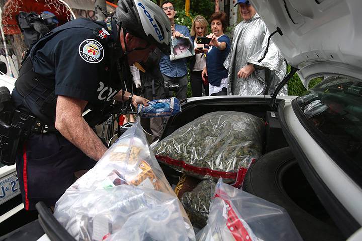 An officer loads up the trunk of a police cruiser with confiscated marijuana and other products in front of the Cannawide marijuana dispensary during a raid by Toronto Police as part of Operation Claudia in Toronto on Thursday, May 26, 2016. 