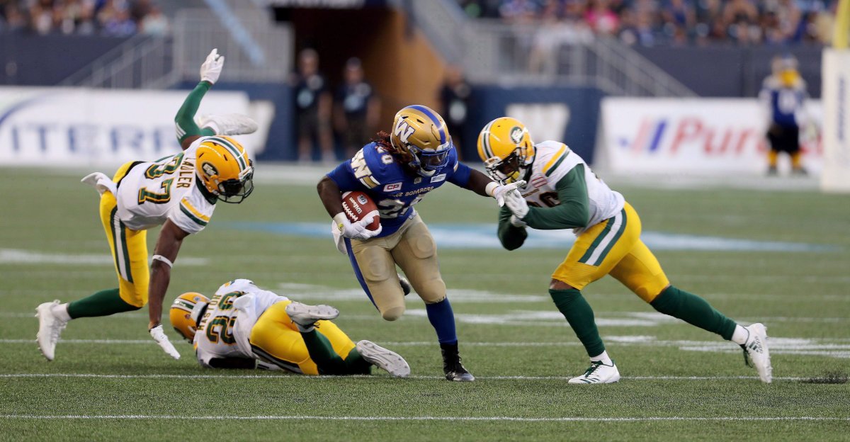 Edmonton Eskimos' Kenny Ladler (37), Mercy Maston (29) and Chris Edwards (26) can't bring down Winnipeg Blue Bombers' Timothy Flanders (20) during the first half of CFL football action in Winnipeg, Thursday, August 17, 2017.