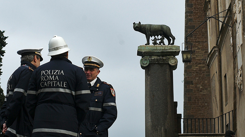 Local policemen stand next to a statue representing the Capitoline wolf outside Rome’s city hall, “Campidoglio” (the Capitoline hill), on December 5, 2014 in Rome.