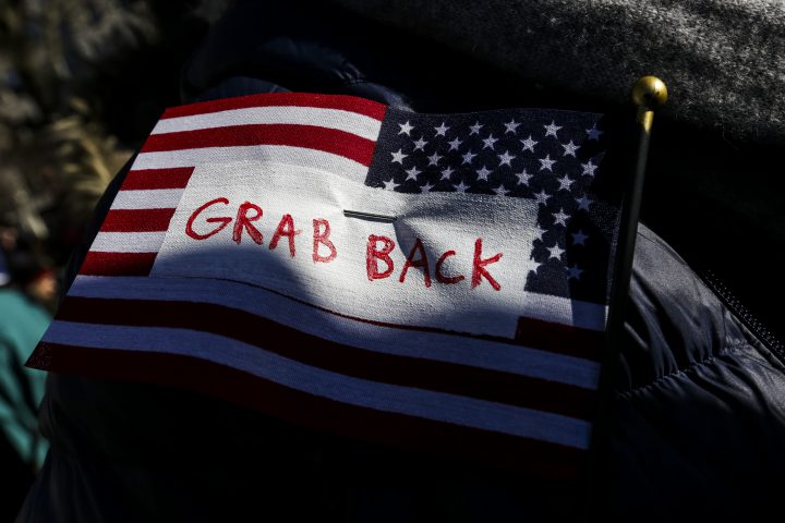 A demonstrator wears an American flag that reads “Grab Back” during the Solidarity Rally for the General Strike in New York, U.S., on Friday, Feb. 17, 2017.
