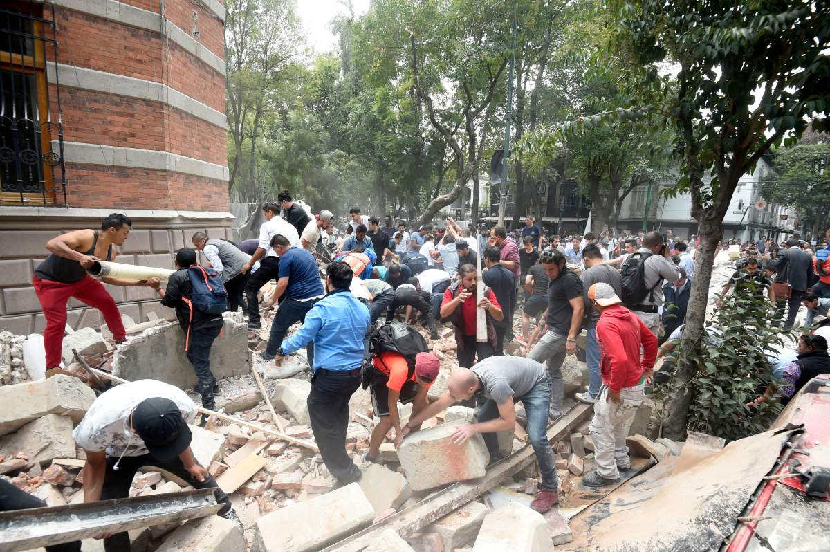 People remove debris of a damaged building after a real quake rattled Mexico City on September 19, 2017 while an earthquake drill was being held in the capital.
