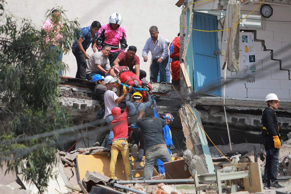MEXICO CITY, MEXICO – SEPTEMBER 19: Rescuers and residents of Colonia Condesa carry a woman on stretcher amid the ruins of a building knocked down by a magnitude 7.1 earthquake that jolted central Mexico damaging buildings, knocking out power and causing alarm throughout the capital on September 19, 2017 in Mexico City, Mexico. The earthquake comes 32 years after a magnitude-8.0 earthquake hit on September 19, 1985. (Photo by Hector Vivas/Getty Images)