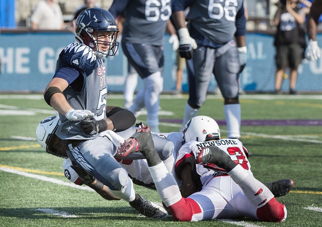 Montreal Alouettes quarterback Drew Willy, centre, is pulled down by Ottawa Redblacks' Avery Ellis, left, and Jonathan Newsome during second half CFL football action in Montreal, Sunday, September 17, 2017.