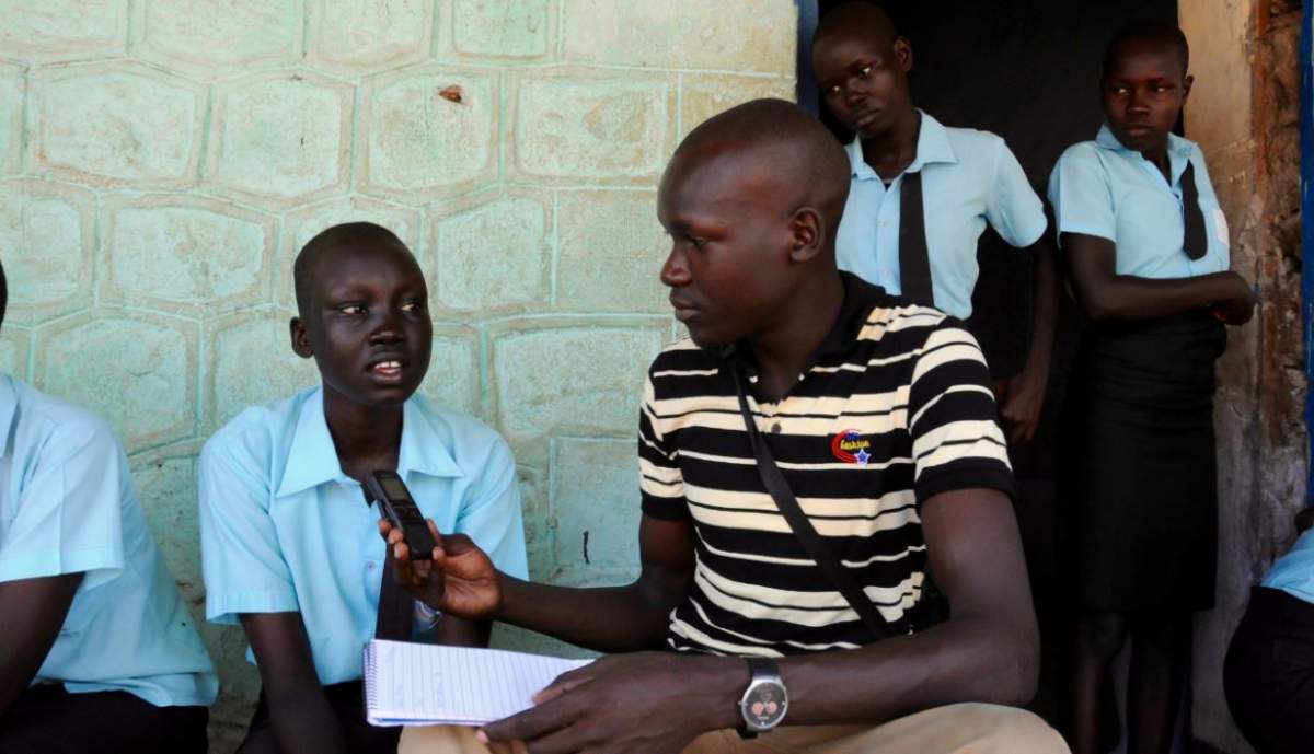 Jale Richard with school student while reporting a story.