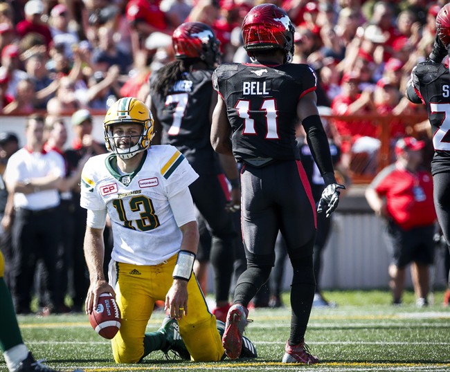 Edmonton Eskimos' quarterback Mike Reilly, left, picks himself up after being sacked by Calgary Stampeders' Junior Turner, centre, and teammate Josh Bell during second half CFL football action in Calgary, Monday, Sept. 4, 2017. 