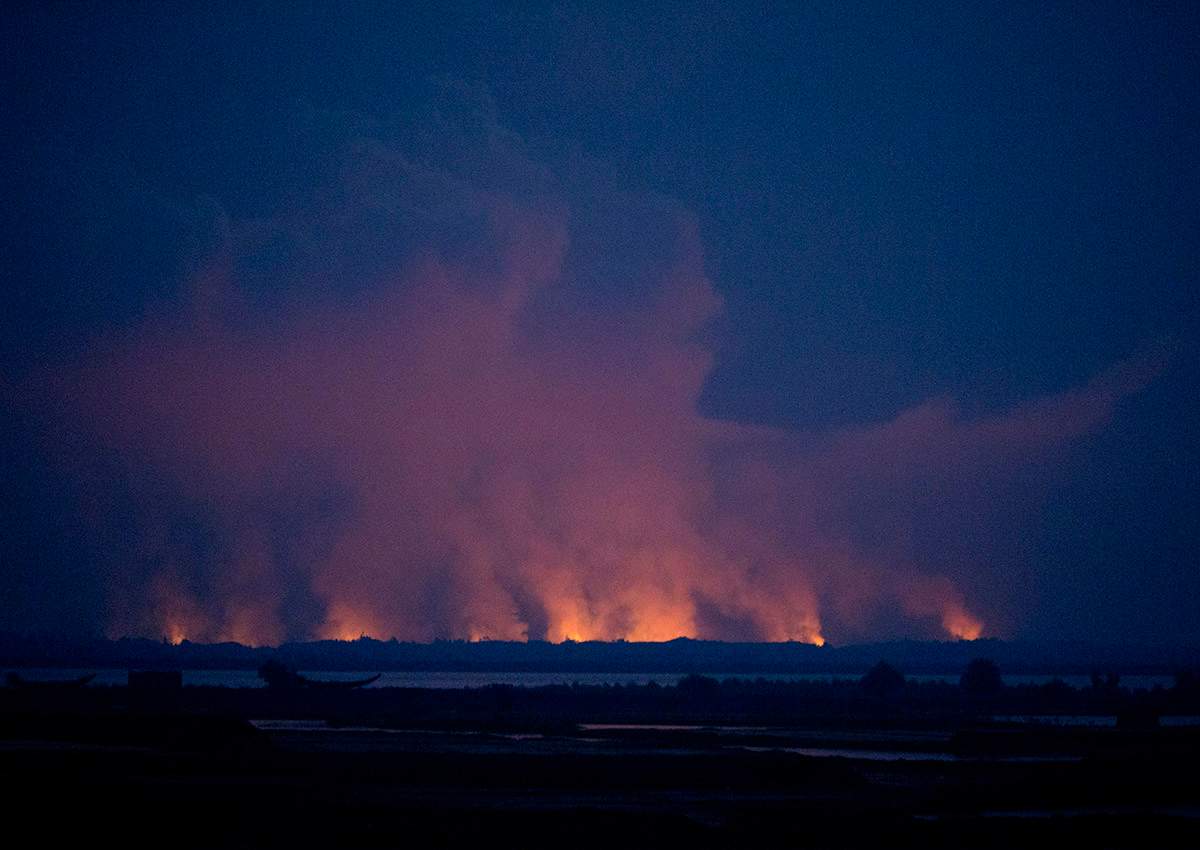 In this Sept. 3, 2017, file photo, smoke and flames in Myanmar are visible from the Bangladeshi side of the border near Cox's Bazar's Teknaf area.