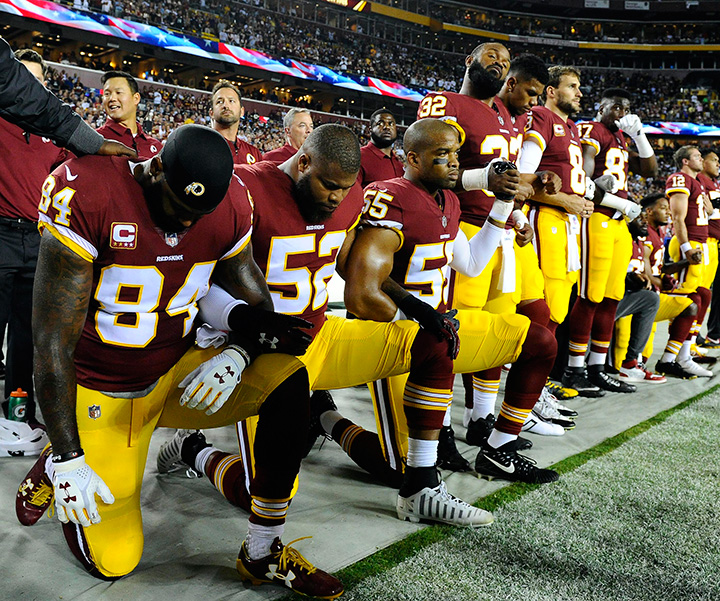 Washington Redskins teammates take a knee during the playing of the national anthem before their game against the Oakland Raiders at FedEx Field.  