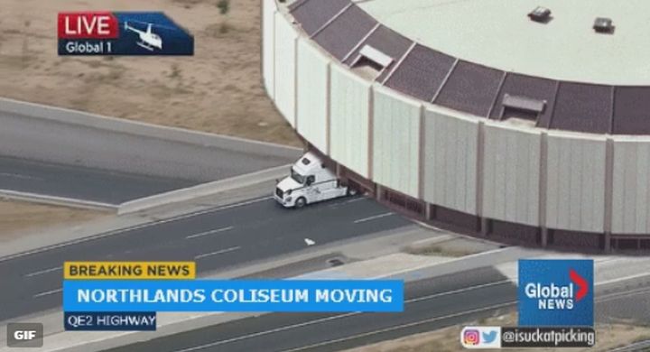 A GIF of a fake live shot from Global Edmonton's News 1 helicopter showing a semi-truck hauling Northlands Coliseum down a highway.