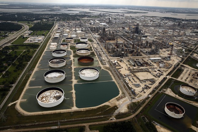 FILE - In this Wednesday, Aug. 30, 2017 file photo, large storage tanks situated in retention ponds are surrounded by rainwater left behind by Tropical Storm Harvey at ExxonMobil's refinery in Baytown, Texas.