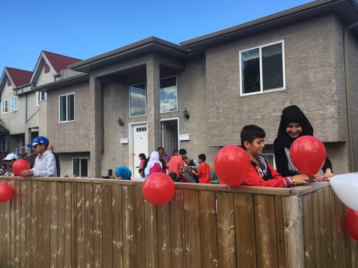 New Canadians hang balloons on a fence that was painted with racist graffiti in September. 