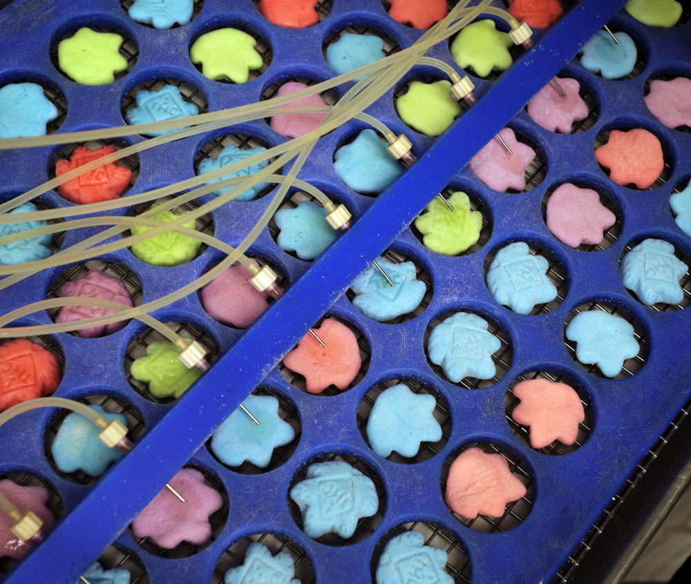 Drops of marijuana extract are placed on candy in the kitchen of AmeriCanna Edibles in Boulder, Colo.