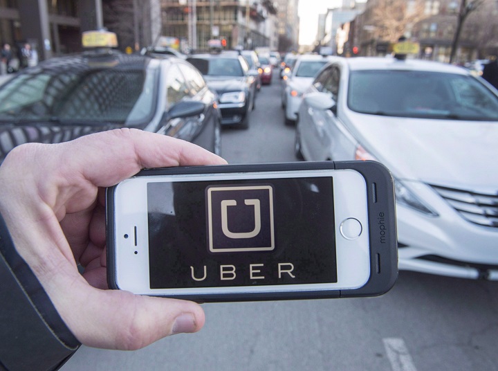 In this file photo, The Uber logo is seen in front of protesting taxi drivers at the courthouse Tuesday, February 2, 2016 in Montreal. 