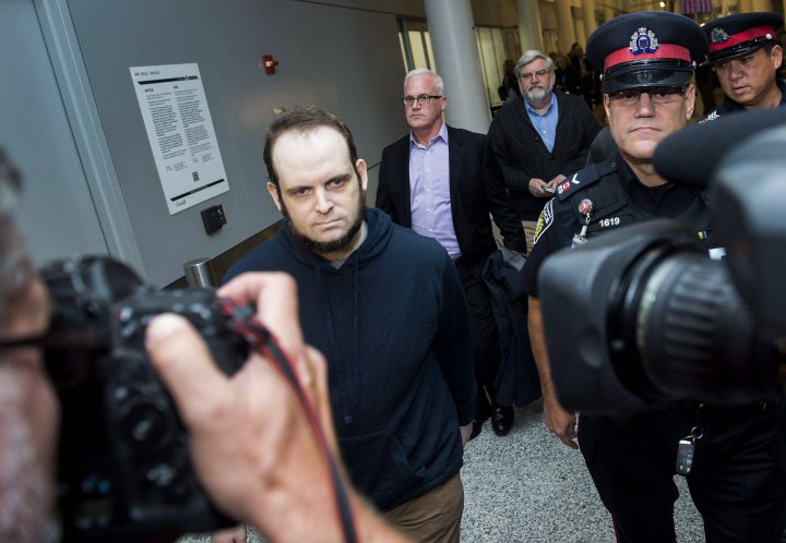 Joshua Boyle, left, gets a police escort after speaking to the media after arriving at the airport in Toronto on Friday, October 13, 2017. Boyle, His wife and and three children had been held hostage for five years by the Taliban-linked Haqqani network in Afghanistan. THE CANADIAN PRESS/Nathan Denette.