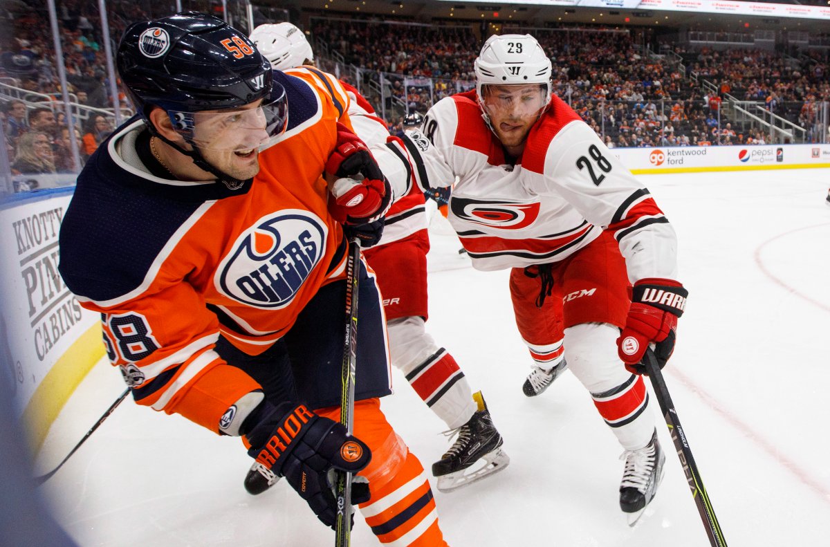 Carolina Hurricanes' Elias Lindholm (28) and Edmonton Oilers' Anton Slepyshev (58) battle for the puck during second period NHL action in Edmonton, Alta., on Tuesday October 17, 2017. THE CANADIAN PRESS/Jason Franson.