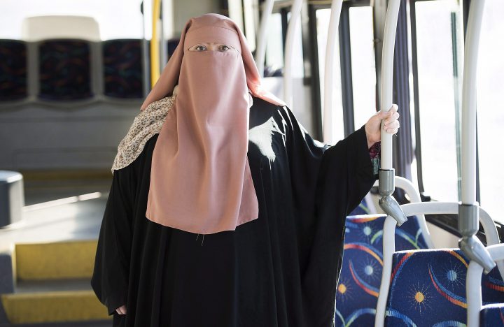 Warda Naili, a niqab-wearing Quebec woman, poses for a photo on a city bus in Montreal, on Oct. 21, 2017.